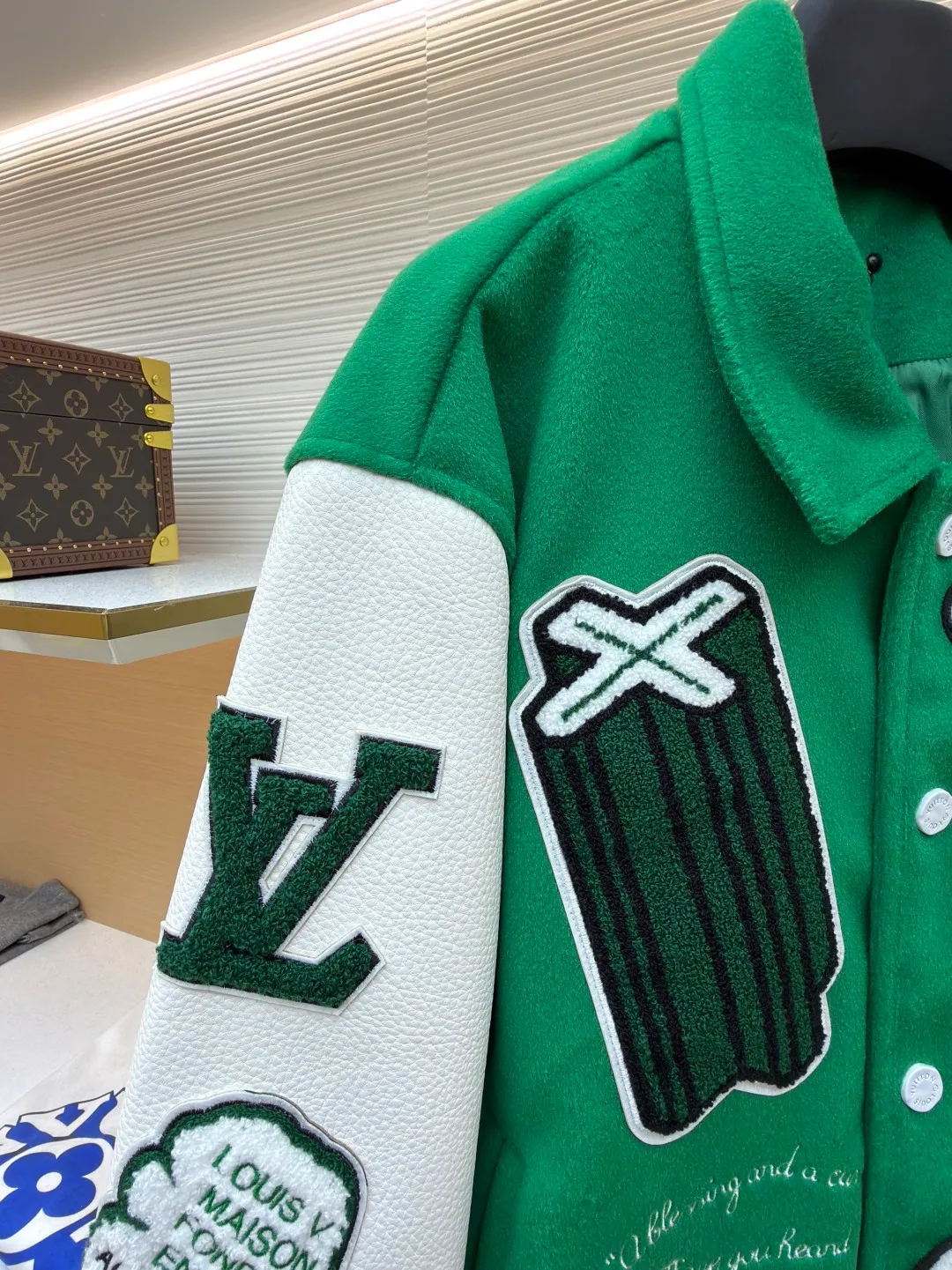LOUIS VUITTON Loose long-sleeved baseball jersey with monogram pattern ●Original version: Purchased and developed for 29999 ●Item number: 1682254-C10 ●Fabric: cotton fabric ●Technology: embroidery production ●Color: green ●Version: fitted version ●Weight: about 1145 grams ●Size: 46-48-50-52 ●Description: The main body of this Louis Vuitton baseball jacket is made of high-count wool blended fabric. It has been processed by raising and carding processes. The fabric has a full velvety feel and is crisp and stylish. The green base color is made of worsted dyeing process. The color is pure and not easy to fade. The sleeves are spliced ​​with custom pebbled artificial leather, which has been embossed and softened. The texture is natural, flexible to the touch, and is scratch-resistant and wear-resistant. The letters and patterns decorated on the body are made of terry embroidery + appliqué embroidery composite technology. The terry embroidery coils are fluffy and three-dimensional, and the edges of the appliqué embroidery are overlocked to ensure accurate pattern splicing. The handwritten text is made using flat embroidery technology, with fine stitches and clear fonts. The placket is made of custom-made mother-of-pearl buttons, which are hand-polished and polished to have a warm luster; the ribbed neckline and hem are made of spandex blended material, which has good resilience and is not easy to loosen. The overall design uses three-dimensional tailoring and hand-sewing techniques to integrate a variety of materials and embroidery techniques to fully demonstrate the essence of haute couture garments. The overall wiring is straight and delicate, the fabric is comfortable and soft, and the color is consistent without color difference. It can be matched with the same style to create a fashionable look and control various occasions. Customized accessories, complete with three standards, same style for men and women!
